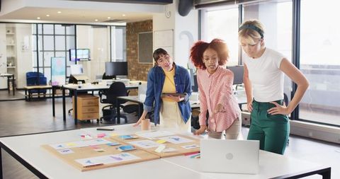 Diverse female team collaborating on creative project in modern office