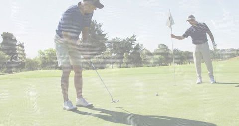 Lining up crucial putt on sunny putting green with partner holding flagstick