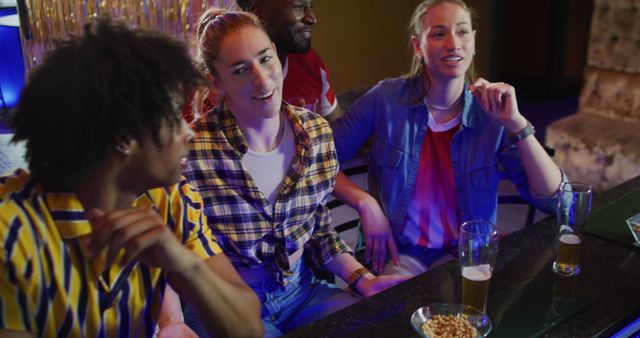 Diverse group of friends sitting at bar, enjoying drinks and laughing. Perfect for depicting social gatherings, casual outings, friendships, nightlife, and entertainment.