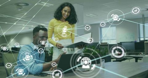 Colleagues collaborating over laptop with digital network overlay, modern open-plan office