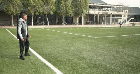 Coach Instructs on Soccer Field with Practicing Players in Background - Download Free Stock Images Pikwizard.com