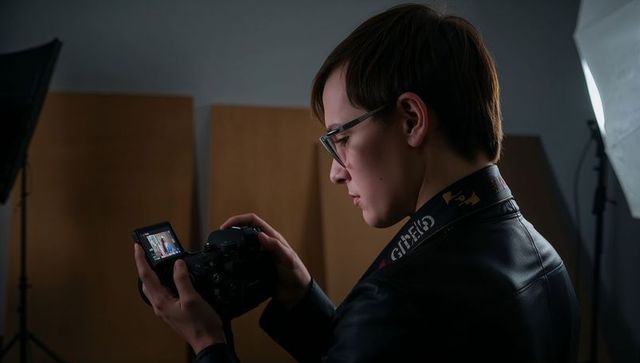 Teen photographer reviewing dslr shots in studio with tilt screen softbox and modern gear