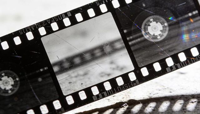 Close-up vintage 35mm film strip showing scratches, sprocket holes and iridescence
