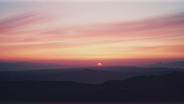 Stunning Sunset Over Mountainous Landscape with Soft Pink and Purple Skies