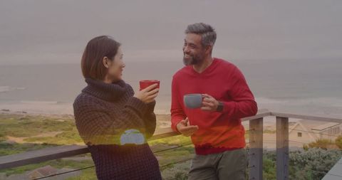 Smiling Couple Relaxing with Warm Beverages by the Ocean