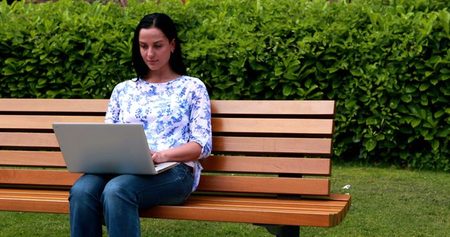 Woman working on laptop while sitting on bench in park - Download Free Stock Images Pikwizard.com