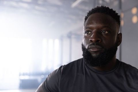 Focused african american athlete training in industrial gym backlit closeup portrait