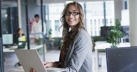 Business woman smiling with laptop in modern office environment