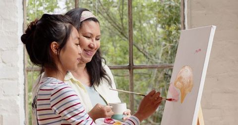 Mother and daughter painting together in light-filled studio