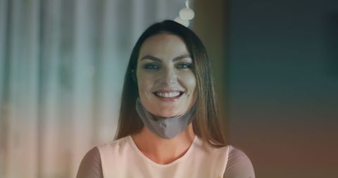 Smiling Woman Wearing Face Mask in Dimly Lit Room - Download Free Stock Images Pikwizard.com