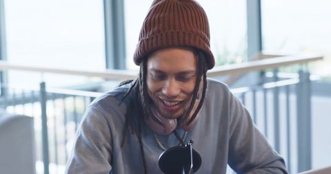 African american smiling man recording podcast in coworking lounge with mic and headphones