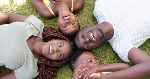 African American Family Smiling Together on Grass Outdoors