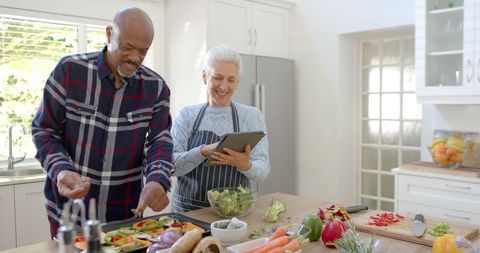 Senior Couple Cooking Together Using Tablet for Recipe