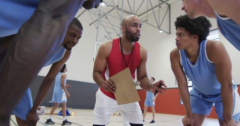 Focused basketball coach giving strategy tips to team
