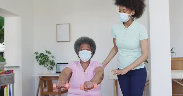 Senior woman exercising with nurse, wearing masks during home physical therapy session - Download Free Stock Images Pikwizard.com