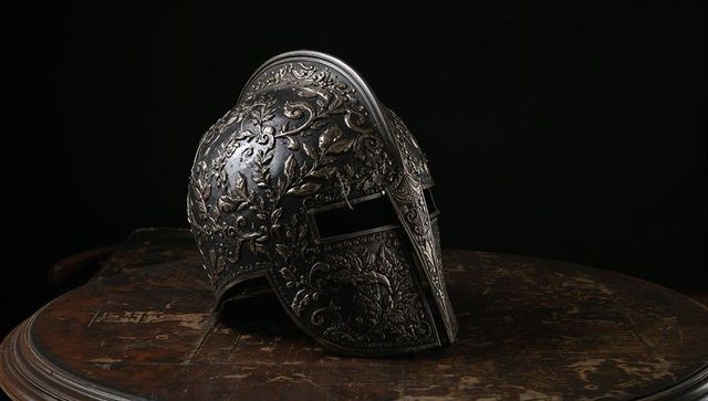 Intricately engraved antique metal helmet on wooden table