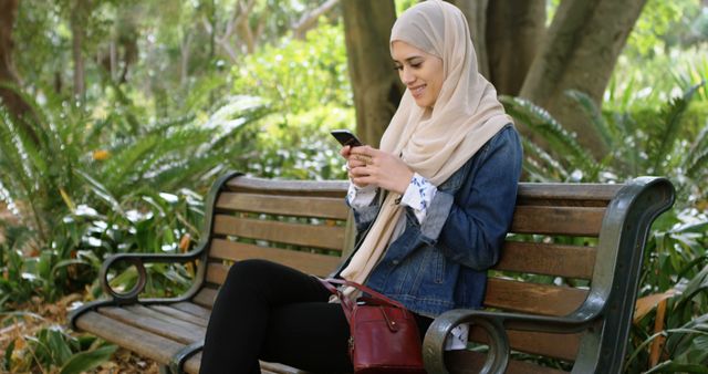 Happy Muslim Woman Sitting on Park Bench Using Smartphone - Download Free Stock Images Pikwizard.com