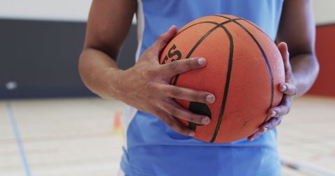 Athlete Holding Basketball on Indoor Court Ready for Game