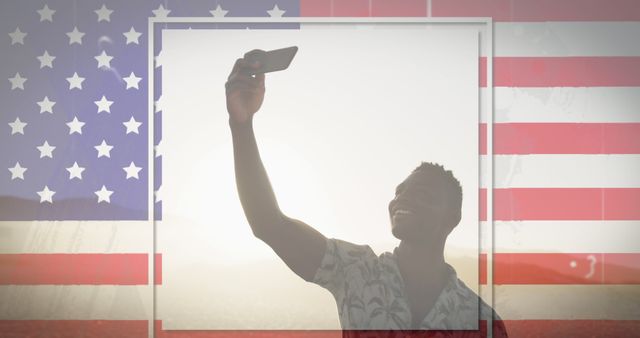 African American man happily taking a selfie against a background of a USA flag, representing patriotic spirit and national pride. Ideal for use in patriotic advertisements, social media campaigns, and promotional materials for Independence Day or other American holidays.