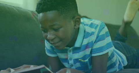 Young Boy Reading on Couch Amidst Digital Overlay of Symbols