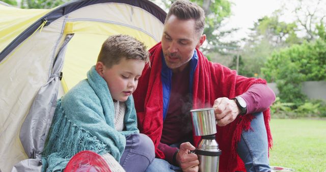 Happy caucasian father with son sitting in tent and drinking tea in garden - Download Free Stock Photos Pikwizard.com