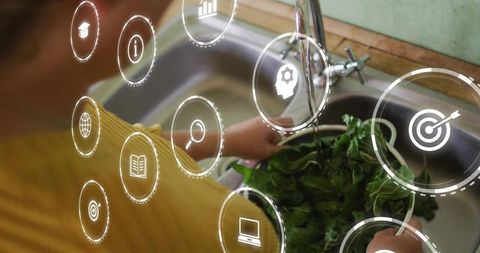 Woman rinsing leafy greens at kitchen sink with running faucet and digital hud icons