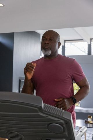 Senior Man Running on Treadmill in Home Gym with Smartwatch
