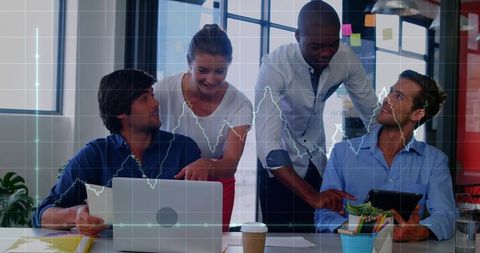 Diverse team collaborating on data analytics using laptop and tablet in modern office