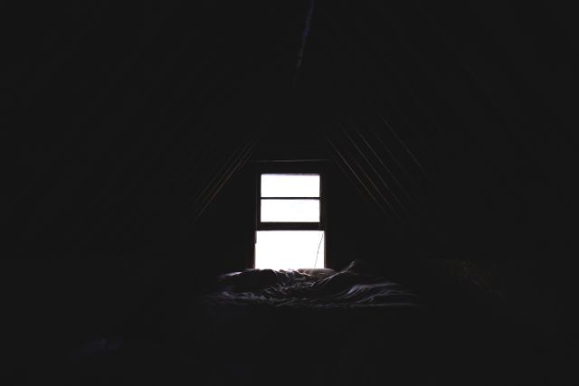 This dark, dimly lit attic room with a small window creates a mood of mystery and calmness. Perfect for themes of solitude, forgotten places, or vintage and rustic settings. Useful for storytelling, design projects, or as a background for texts and quotes.