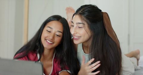 Friends Enjoying Tablet Together on Cozy Bedroom Bed