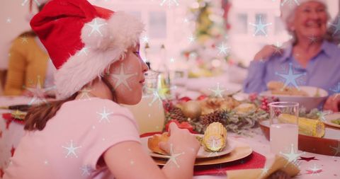Family gathers for festive Christmas dinner, wearing Santa hats and surrounded by holiday decorations. Snow overlay adds whimsical holiday cheer to scene. Perfect for promoting seasonal traditions, holiday celebration advertisements, or illustrating joy of family gatherings during winter festivities.