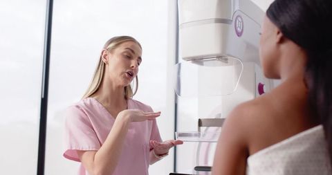 Radiology technologist explaining mammography positioning to patient in modern clinic
