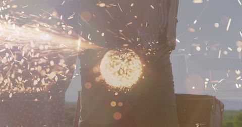 Woman operating angle grinder outdoors producing flying sparks at industrial worksite