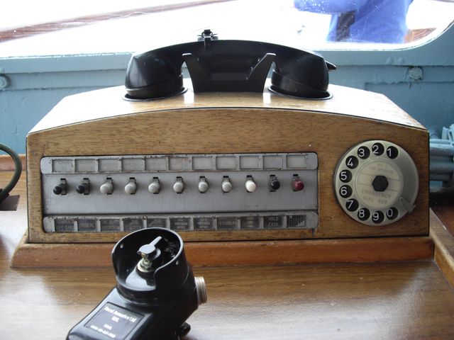 This shows vintage ship communication equipment, including a rotary dial telephone and other control buttons. Good for illustrating maritime history, navigation technology, and retro-themed projects.