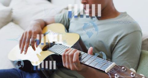 Man strumming acoustic guitar on sofa with digital overlays, relaxing home musician