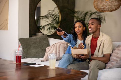 Relaxed Couple Eating Takeout and Watching TV on Cozy Sofa