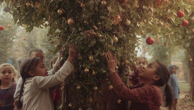 Children Decorating Outdoor Tree with Festive Baubles