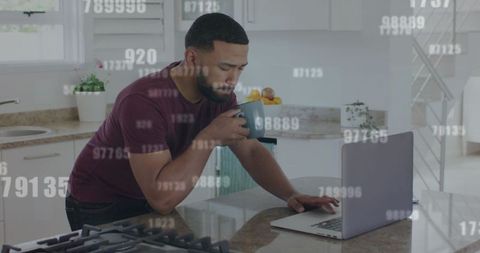 Man Analyzing Data on Laptop in Modern Kitchen