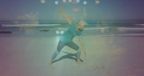 Senior woman stretching on beach practicing yoga by ocean with sunlit bokeh