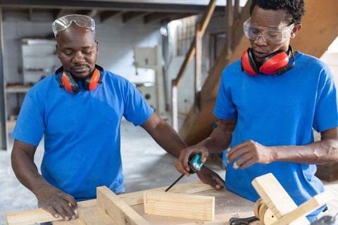 African american carpenters measuring wood planks at workshop bench for precision joinery