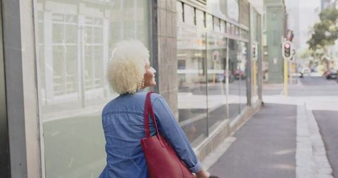 Woman with Red Tote Stands by Bike on Urban Street