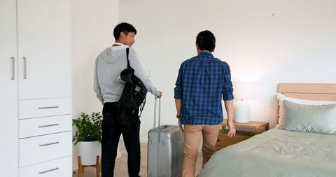 Young Men Packing Suitcase for Travel Adventure in Bedroom