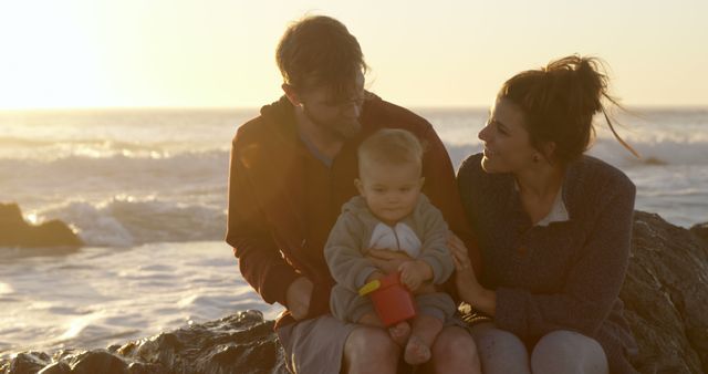 Happy Family Sitting on Rocks Near Ocean at Sunset - Download Free Stock Images Pikwizard.com