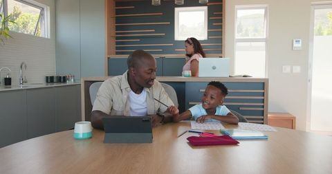 Father and Son Connecting Over Tablet While Mother Works Nearby at Home