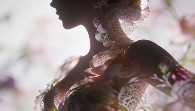 Backlit floral silhouette model wearing lace petal body art, ethereal pastel couture
