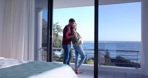 Expecting Couple Embracing on Balcony Overlooking Ocean
