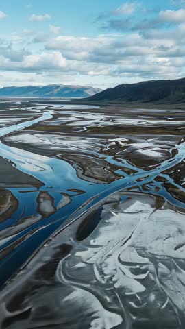 Vertical drone video capturing braided river channels and silt bars on muddy floodplain