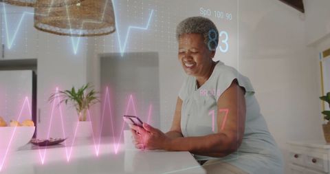 senior african american woman sitting at home using her smartphone to monitor health data such as heart rate and respiratory rate. cardiograph overlay emphasizes digital health monitoring and technology integration in personal care. useful for illustrating modern healthcare technologies, aging wellness, or showcasing smart health apps in marketing materials.