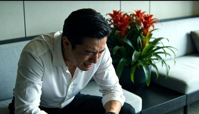 Businessman leaning forward showing emotional distress in modern office lounge