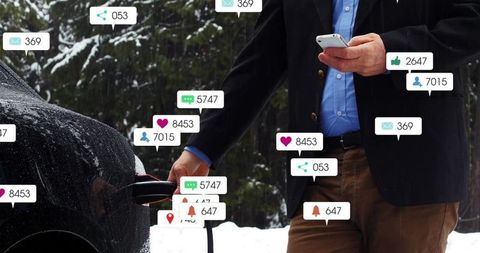 Man Charging Electric Car Using Smartphone in Snowy Forest